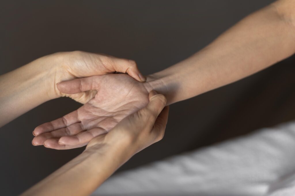 A imagem mostra duas mãos segurando outra mão com tendinite e fazendo massagem.